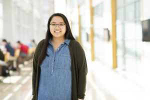 Woman poses in bright hallway in UNL College of Business.