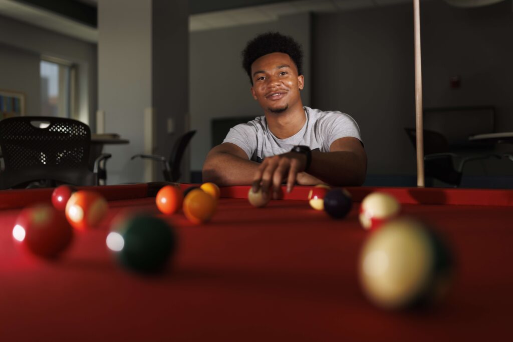 Dywan Williams poses for photo in front of pool table.