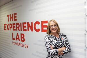 Shari R. Veil, MBA, Ph.D. poses in front of the Experience Lab in the UNL College of Journalism.